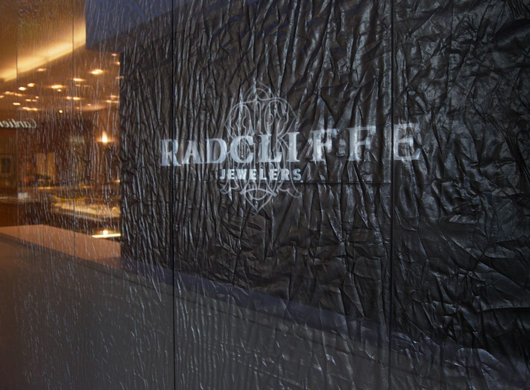 The elegant effect created by Archetype Glass' custom fabric laminated glass partition wall for Radcliffe Jewelers boutique retail entrance